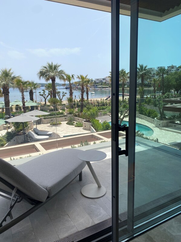 A balcony with a view of a marina, palm trees, and a swimming pool.