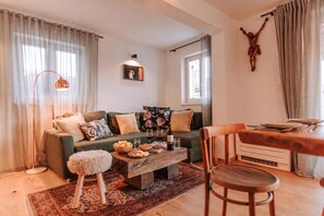 A cozy living room with a green sofa, a wooden coffee table, and a dining table with chairs. - Istrian Villa Beatrice Near Pula (Vodnjan)
