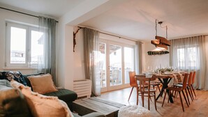 A modern living room with a sofa, a dining table set for six, and a sliding glass door leading to an outdoor area. - Istrian Villa Beatrice Near Pula (Vodnjan)