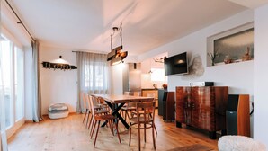 A modern dining area with a wooden table and chairs, a hanging light fixture, and a television mounted on the wall. - Istrian Villa Beatrice Near Pula (Vodnjan)