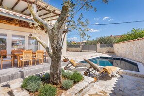 A poolside area with a tree, lounge chairs, and a dining table with chairs. - Istrian Villa Beatrice Near Pula (Vodnjan)