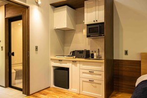 A compact kitchen with white cabinets, a microwave, and a small refrigerator.