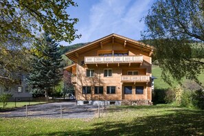 Un edificio in legno a più piani con balconi, circondato da alberi e un'area verde.