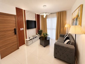 A modern living room with a flat-screen TV, a grey sofa, a coffee table, and a lamp. - Modern Cozy apartment (Boca Chica)