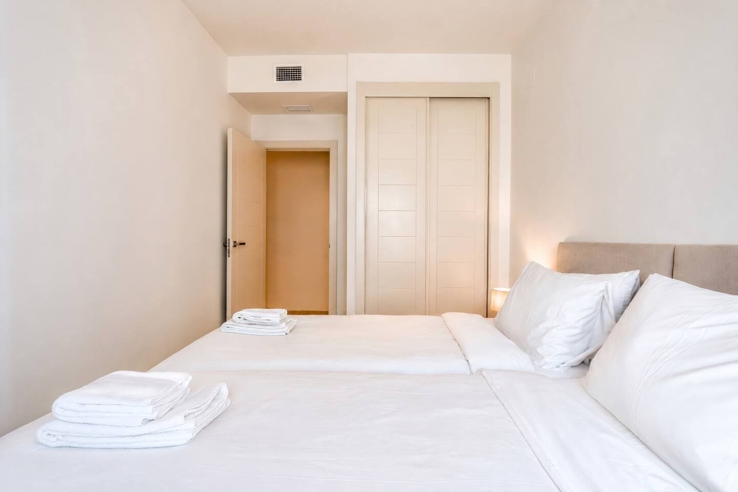 A hotel room with a bed, a nightstand, a door, and a closet.