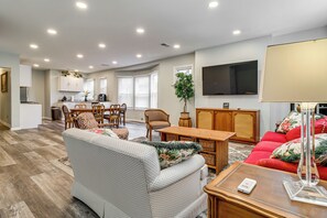Un salon moderne avec un canapé, un divan rouge, une table basse en bois et un téléviseur fixé au mur.