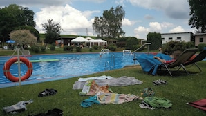 A swimming pool with a lifebuoy, lounge chairs, and scattered items on the grass. - Vacation on the farm (2P) (Hohenleuben)