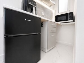 A modern kitchen with a black refrigerator, white cabinetry, and a microwave.