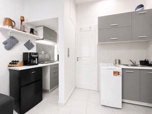 A compact kitchen with a dishwasher, coffee machine, and a microwave.