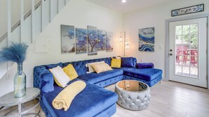 Ein modernes Wohnzimmer mit einem blauen Modulsessel, einem runden Hocker und einer Treppe.