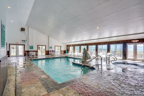 Ein Innenpool mit Meerblick, eine Whirlwanne und eine Sitzecke mit Tischen und Stühlen.