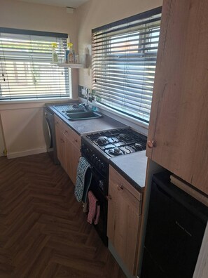 Cocina con estufa a gas, pileta y armarios de madera.