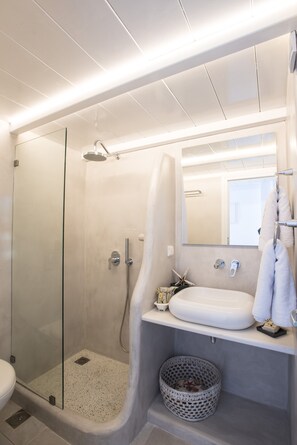 Uma casa de banho moderna com cabine de duche em vidro, lavatório branco e espelho grande.