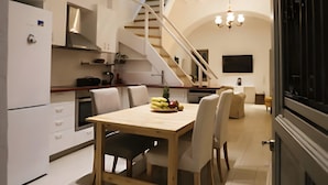 Eine moderne Küche mit Essbereich, einer Treppe und einem an der Wand befestigten Fernseher.