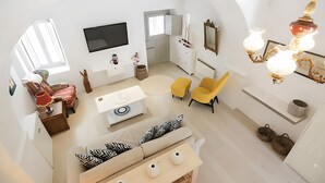Ein modernes Wohnzimmer mit einer Couch, Sesseln, einem Fernseher und einem einzigartigen Kronleuchter.