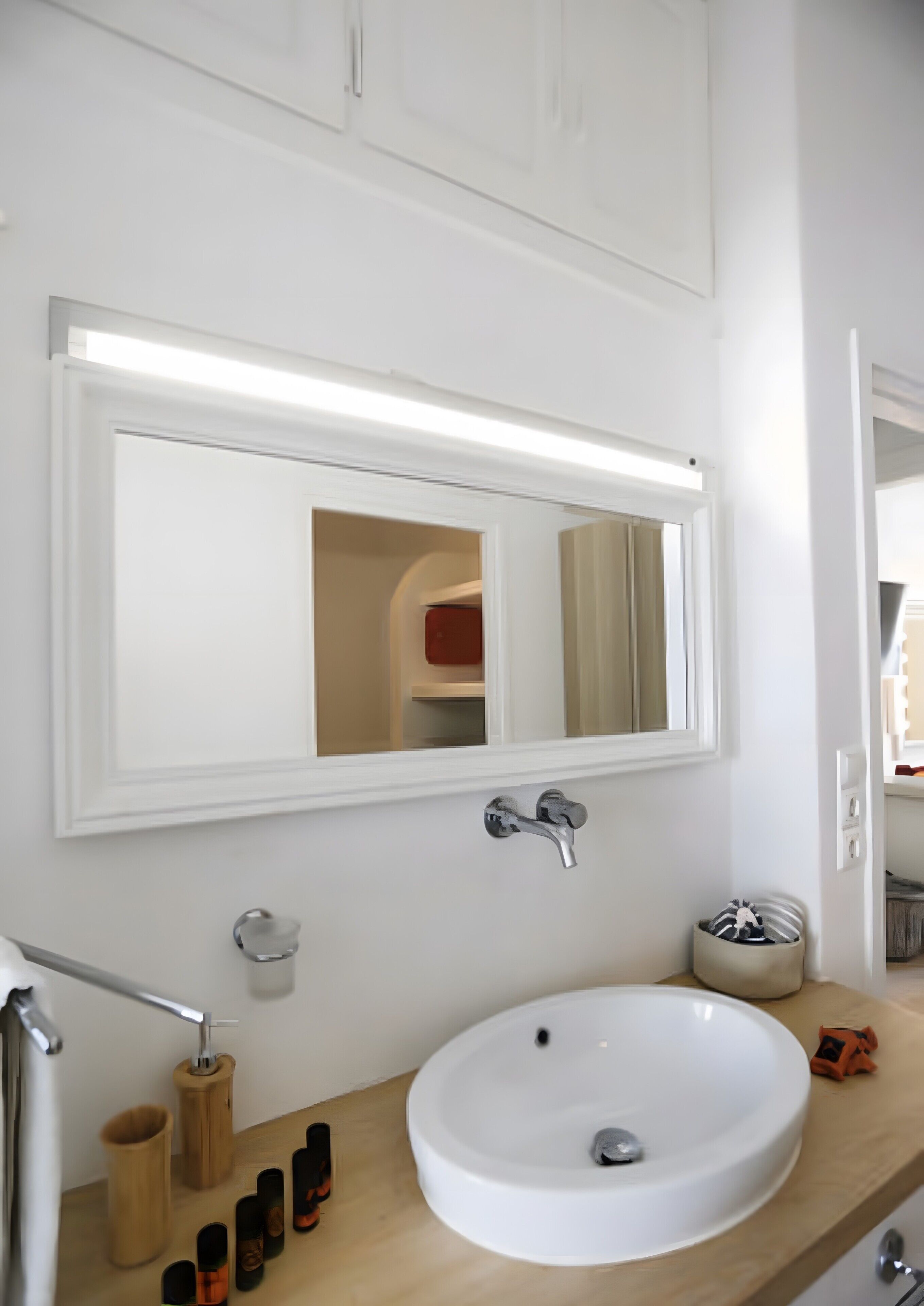 A bathroom with a white sink, a mirror, a towel rack, and a wooden vanity.