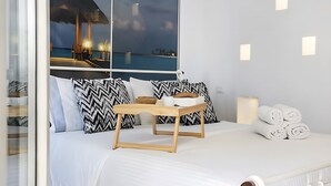 Ein Bett mit einer Holzbank, gemusterten Kissen und aufgerollten Handtüchern.