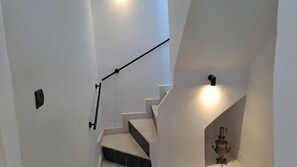 A staircase with a handrail, a wall-mounted light, and a decorative object.