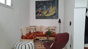 Una sala de estar con un sofá, sillones, una mesa de centro y un cuadro en la pared.