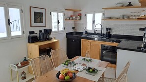 A compact kitchen with a dining area, featuring a coffee maker, toaster, and a sink.
