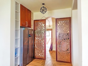 A kitchen with a refrigerator, wooden cabinets, and a decorative partition.