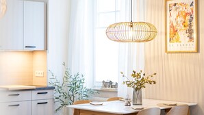 A modern dining area with a table, chairs, a hanging light fixture, and a framed artwork on the wall. - Vacation apartment M6 - "Kommodig Oorloff" - 3-room apartment close to the beach for 4 people (Graal-Müritz)