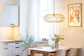 Ein moderner Essbereich mit Tisch, Stühlen, einer Pendelleuchte und einem gerahmten Kunstwerk an der Wand.