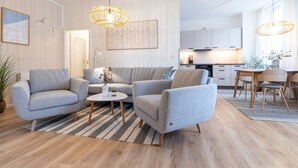 A modern living room with a sofa, armchairs, a coffee table, and a dining area with a table and chairs. - Vacation apartment M6 - "Kommodig Oorloff" - 3-room apartment close to the beach for 4 people (Graal-Müritz)