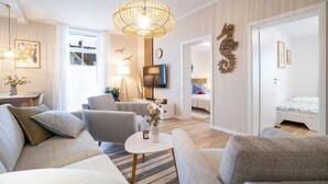 A modern living room with a sofa set, a coffee table, a TV, and a decorative seahorse wall piece. - Vacation apartment M6 - "Kommodig Oorloff" - 3-room apartment close to the beach for 4 people (Graal-Müritz)