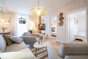 Ein modernes Wohnzimmer mit einer Sofagarnitur, einem Couchtisch, einem Fernseher und einer Wanddekoration in Form eines Seepferds.