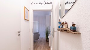A hallway with a door leading to a room, a mirror, and a shelf with small items. - Vacation apartment M6 - "Kommodig Oorloff" - 3-room apartment close to the beach for 4 people (Graal-Müritz)