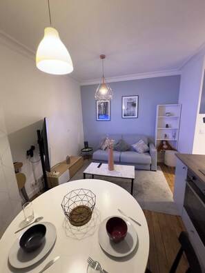 Ein modernes Wohnzimmer mit Essbereich, einem grauen Sofa, einem Couchtisch und einer Pendelleuchte.