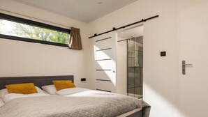 Une chambre à coucher comprenant un lit, une fenêtre, une porte coulissante et un espace douche.