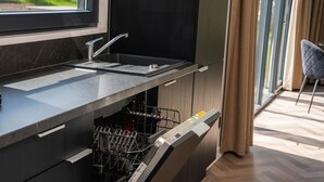 Une cuisine moderne dotée d’un lave-vaisselle intégré, d’une fenêtre offrant une belle vue et d’une chaise dans la pièce adjacente.