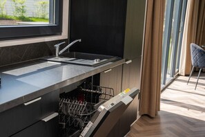 Una cucina moderna con lavastoviglie integrata, una finestra con vista e una sedia nella stanza adiacente.