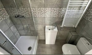 A small bathroom with a shower, toilet, and sink.