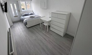 A bedroom with a bed, a desk, and a dresser.