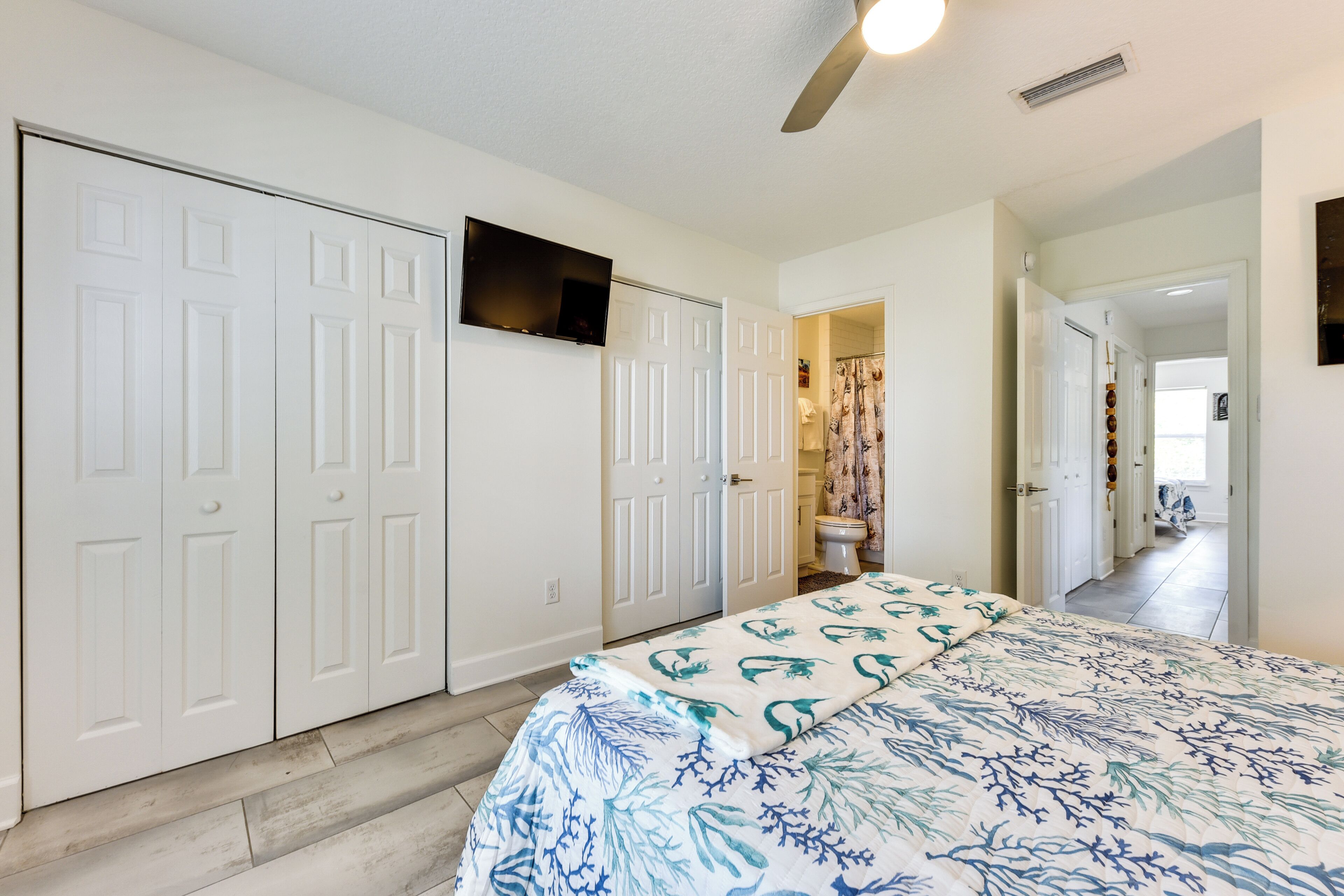 A bedroom with a bed, white wardrobe, and a ceiling fan.