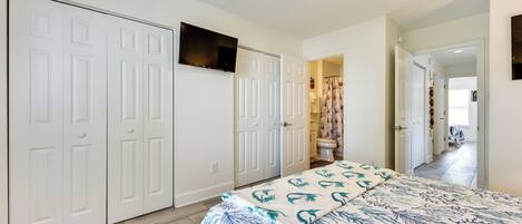 A bedroom with a bed, white wardrobe, and a ceiling fan.