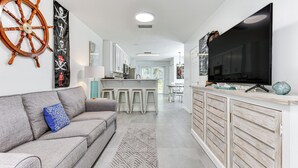 Eine moderne Küche mit großem Fernseher, einer Bar und einem Essbereich.