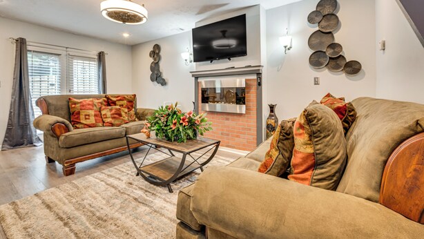 A living room with a sofa, a coffee table, a fireplace, and a television mounted on the wall. - 3BR Townhome Near Downtown Decatur (Decatur)