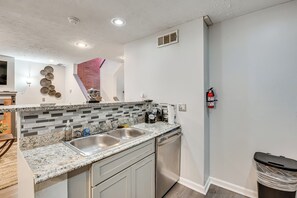 Una cocina con encimera de granito, pileta de acero inoxidable y lavavajillas.