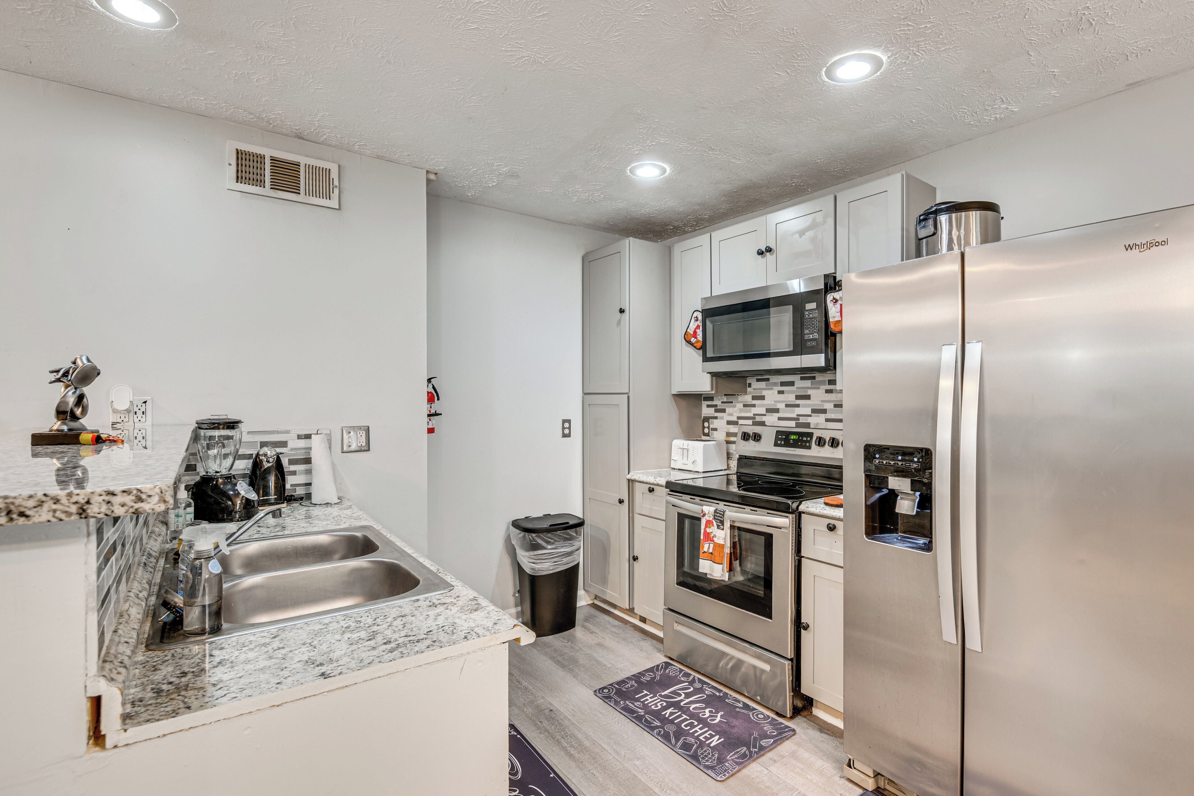 A modern kitchen with a stainless steel refrigerator, microwave, oven, and sink.