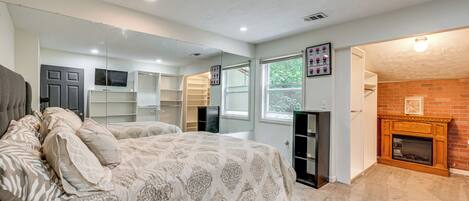 A bedroom with a bed, a fireplace, a mirror, and a closet.
