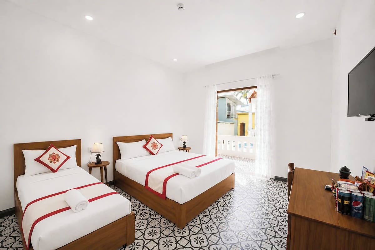 A hotel room with two beds, a TV, a desk with beverages, and a patterned floor.