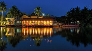 A waterfront hotel with a reflection in the water, palm trees, and a well-lit building. - Sunset Cove Boutique Resort (Phu Quoc)