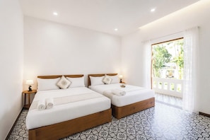 A hotel room with two beds, a large window with curtains, and patterned floor tiles.