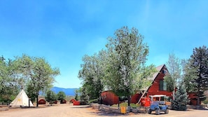 A rustic cabin with a red exterior, surrounded by trees and a clear sky. - Cortez RV Resort (Cortez)