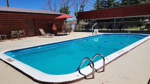 A rectangular swimming pool with a metal ladder, surrounded by a concrete deck.