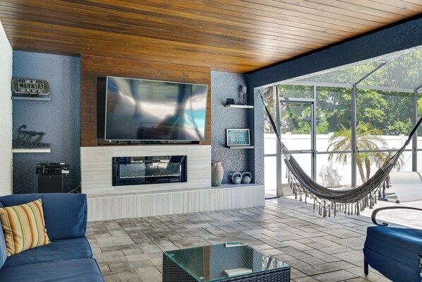 A living room with a TV, sofa, and hammock. - Tropical Oasis in Lehigh Acres: Great for Groups! (Lehigh Acres)
